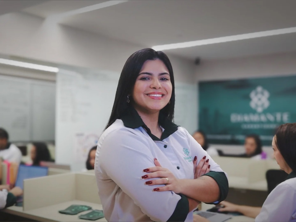 Atendente da Diamante Garantidora no escritório, com a equipe comercial ao fundo