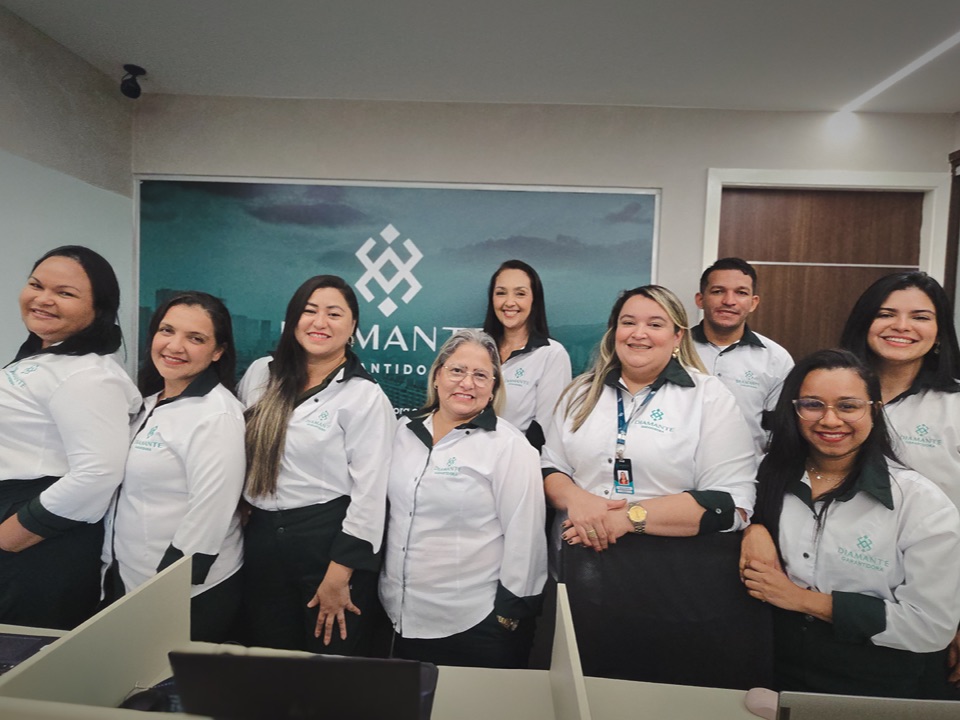 Equipe da Diamante Garantidora reunida na sede, em frente ao painel da empresa